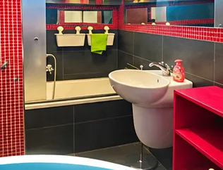 Bagno con vasca, rivestimento a mosaico rosso, lavabo bianco e mobile a giorno