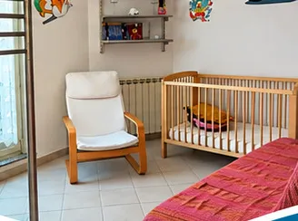 Cameretta con culla in legno, poltroncina, mensole e letto singolo